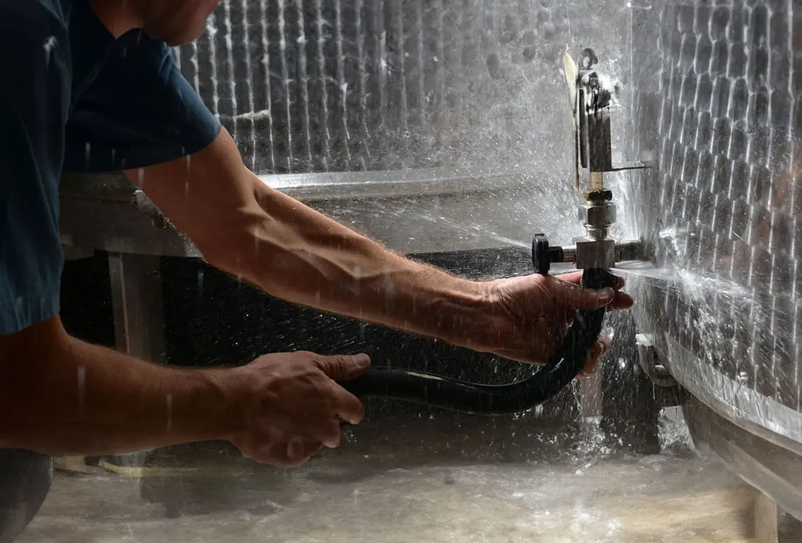 Patrick Graezer branche un tube à une cuve sous pression, faisant jaillir du liquide