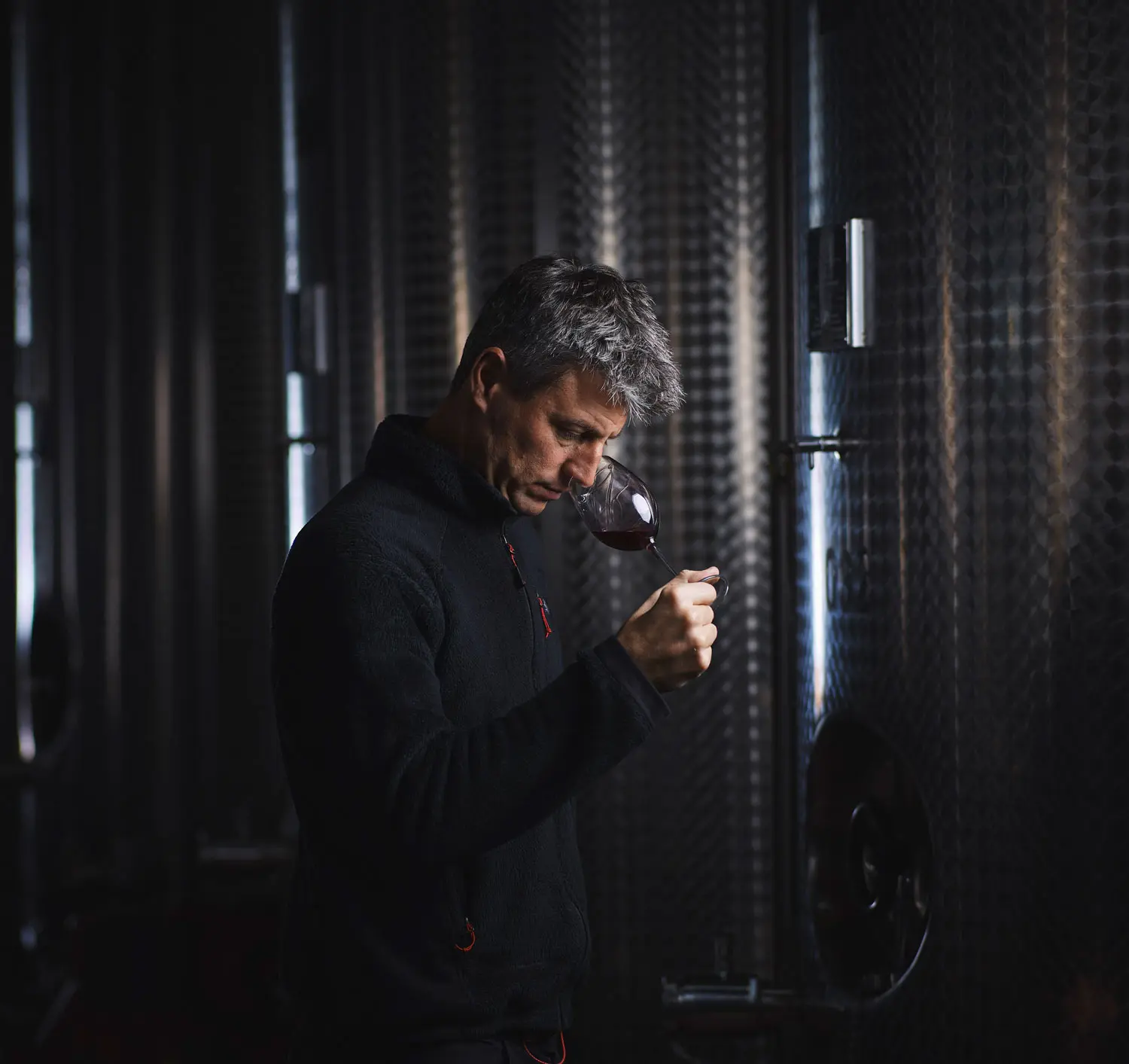 Florian Barthassat entre les cuves analyse les arômes au nez d'un verre de vin